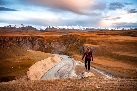 Glaciated and snow-capped mountains, Young woman in mountain landscape with yellow grass in the
