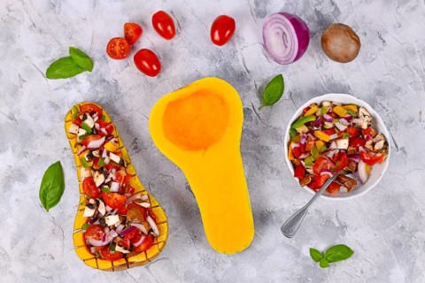 Top view of vegan baked Butternut squash vegetable filled with bell pepper, cherry tomatoes, red