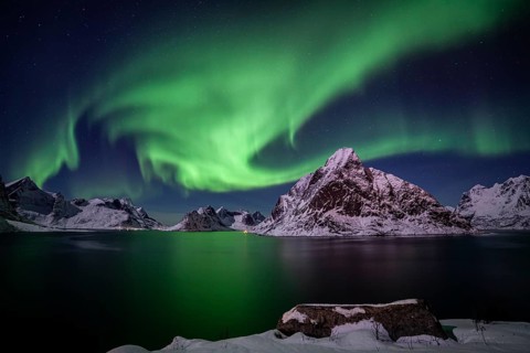 Green northern lights reflected in fjord, steep mountains, aurora borealis, winter, Reine,