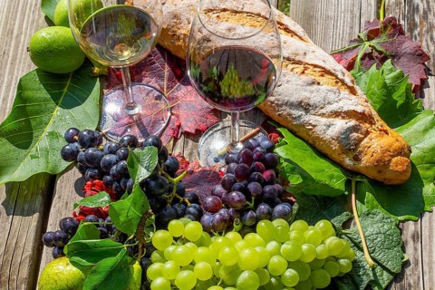 Symbolic image of grape grape harvest: Ripe grapes decorated with wine glasses on a wooden table