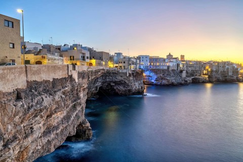 Polignano a Mare with its houses directly on the cliffs after sunset