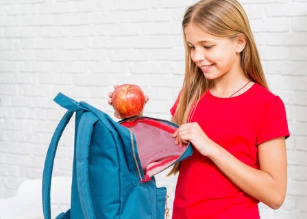 Happy girl putting apple backpack