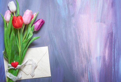 Bouquet of colorful tulips tied with a lace ribbon and a wooden clip with a red heart, and a closed