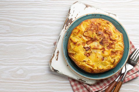 Homemade Spanish tortilla - omelette with potatoes on plate on white wooden rustic background top