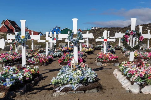 Qeqertarsuaq, Greenland, July 6, 2018: White wooden crosses and artificial flowers on the local
