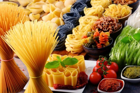 Composition with different sorts of pasta on kitchen table