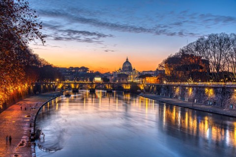 Dramatic sunset over the Basilica of St. Peter and the Tiber in Rome