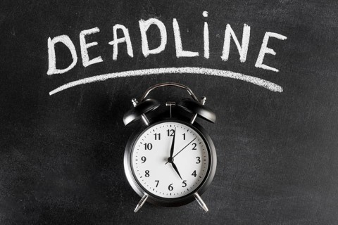 Alarm clock against chalkboard with deadline text
