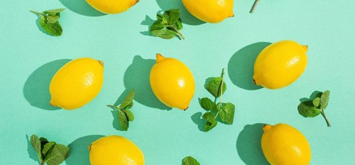 Fresh yellow lemons with mint on minimal blue background on bright sun light with hard shadows