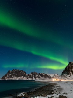 Spectacular dancing green strong northern lights over the famous round boulder beach near Uttakleiv