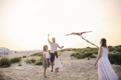 Happy family with parents and kids playing together with snakes on a beach vacation. Summer