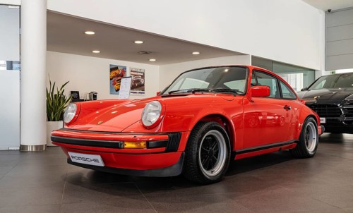 A picture of a red Porsche 911 Carrera 3.0 inside a dealership