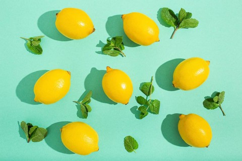 Fresh yellow lemons with mint on minimal blue background on bright sun light with hard shadows
