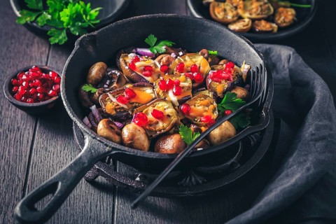 Baked small eggplants, stuffed with mushrooms and pomegranate in baking pan
