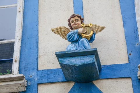 Carved angel with harp on the façade of a half-timbered house in Rue Rene Madec, painted blue,