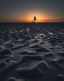 Silhouette of a person with a bicycle on a beach during a picturesque sunset, Tofino, BC, Canada,