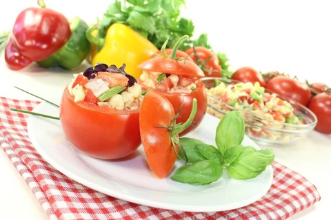 Stuffed tomatoes with pasta salad and peppers on a light-coloured background