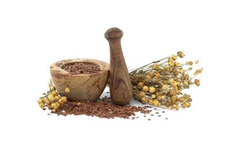 Flaxseed in wooden rustic-style mortar with pestle and bunch of flax plants isolated on white