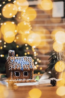 Little homemade gingerbread house with glaze standing on the table with decorations, candles and
