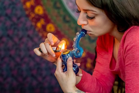 A beautiful brunette model smokes marijuana in the privacy of her own home