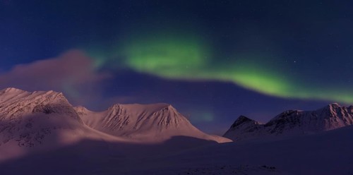 Northern Lights (Aurora borealis) over moonlit mountains in the valley Stuor Reaiddavaggi,