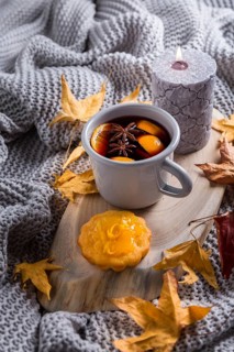 Cosy and soft winter background, with mulled wine, knitted blanket and candle with lemon cake on