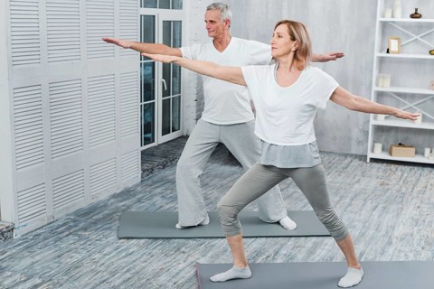 Healthy couple performing exercising yoga mat home