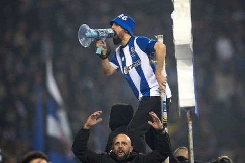 Football match, a fan of FC Porto with jersey on the fence shouting with a megaphone, another fan
