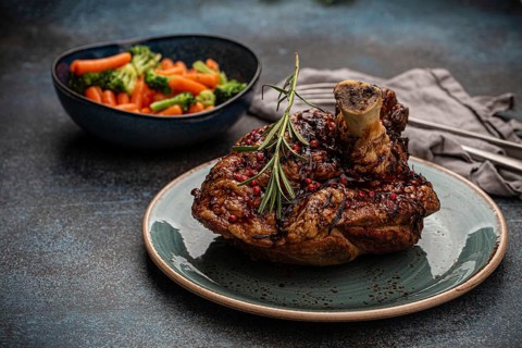 Delicious roasted ham or pork knuckle with glazed brown crispy skin, red pepper berries and
