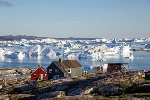 Rodebay, Greenland, July 09, 2018: Colorful wooden houses with icebergs in the background. Rodebay,