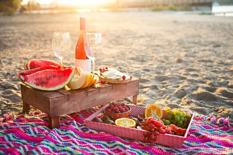 Outdoor picnic with rose wine, fruits, nuts meat and cheese