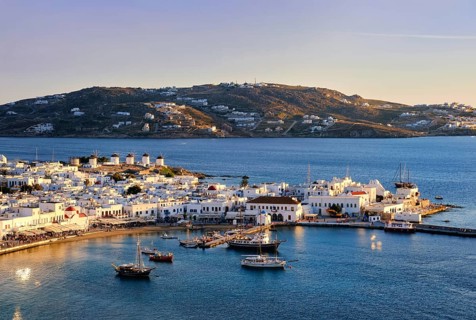 Beautiful sunset view over Chora, main town of Mykonos, Cyclades, Greece and its harbor and port.