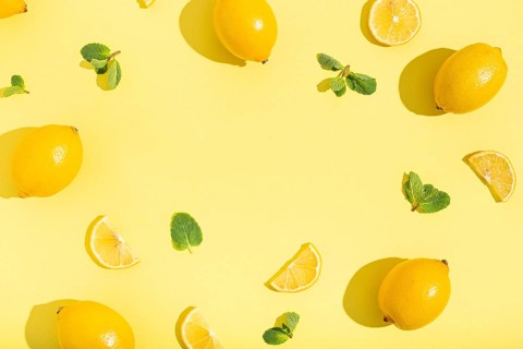 Fresh yellow lemons with mint on minimal beige yellow background on bright sun light with hard