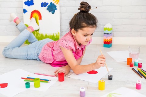 Little girl lying floor painting with water color with paint brush paper