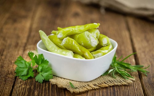 Fresh made Green Chilis (filled with cheese) on an old and rustic wooden table (selective focus,
