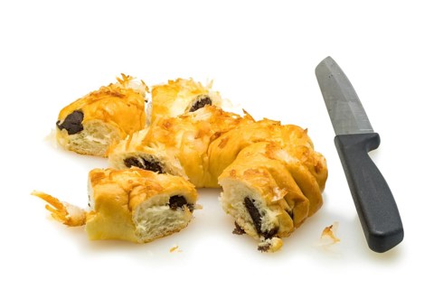 Pieces of bread pudding with coconut and knife on white background