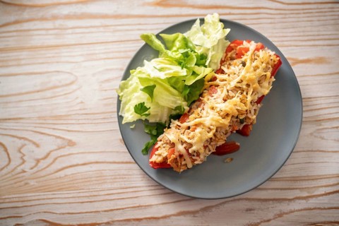 Pointed red bell pepper baked with rice, tuna and cheese, lettuce salad with parsley garnish on a