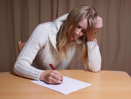 lovesick young woman writing letter with broken heart
