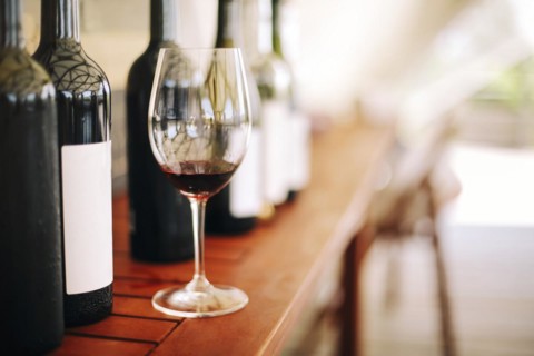 Wine bottles and glass with red wine on wooden table on the garden background in sunny day party