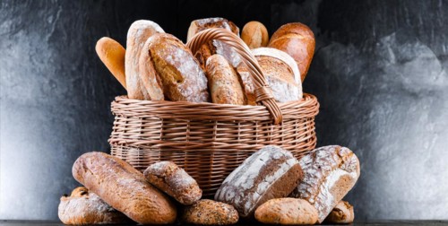 Wicker basket with assorted bakery products including loafs of bread and rolls