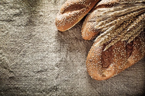 Crusty bread wheat ears on burlap background