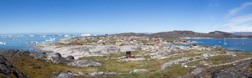 Rodebay, Greenland, July 09, 2018: Colorful wooden houses with icebergs in the background. Rodebay,