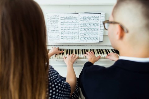Close up couple playing piano with musical sheet