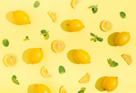 Fresh yellow lemons with mint on minimal beige yellow background on bright sun light with hard