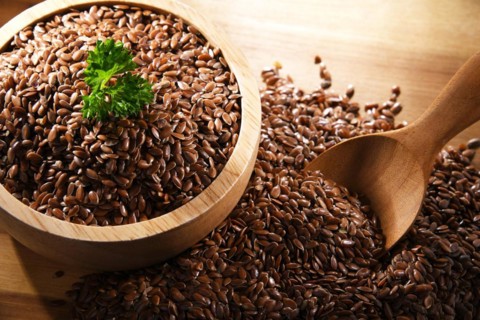 Bowl of brown flax seeds on wooden table