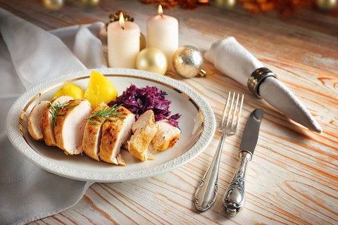 Roast chicken breast with red cabbage and potatoes on a white plate, silverware and napkin on a