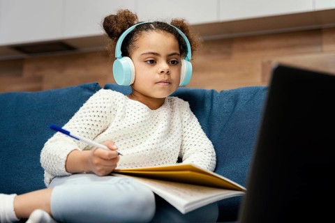 Little girl during online school with laptop headphones