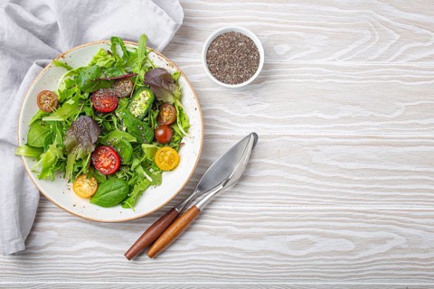 Vegetables vegetarian healthy salad with red yellow cherry tomatoes, green leafs and chia seeds on