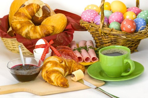 Colourful Easter breakfast with Easter eggs, coffee, croissant, ham and jam