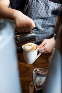 Professional barista pouring latte foam coffee caf